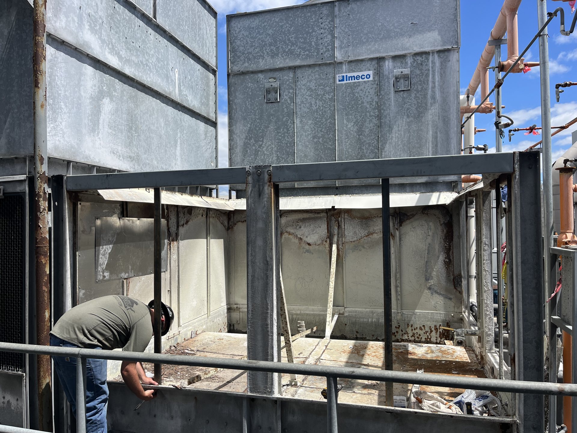 Worker cutting steel on a rooftop cooling tower structure during industrial maintenance in Virginia