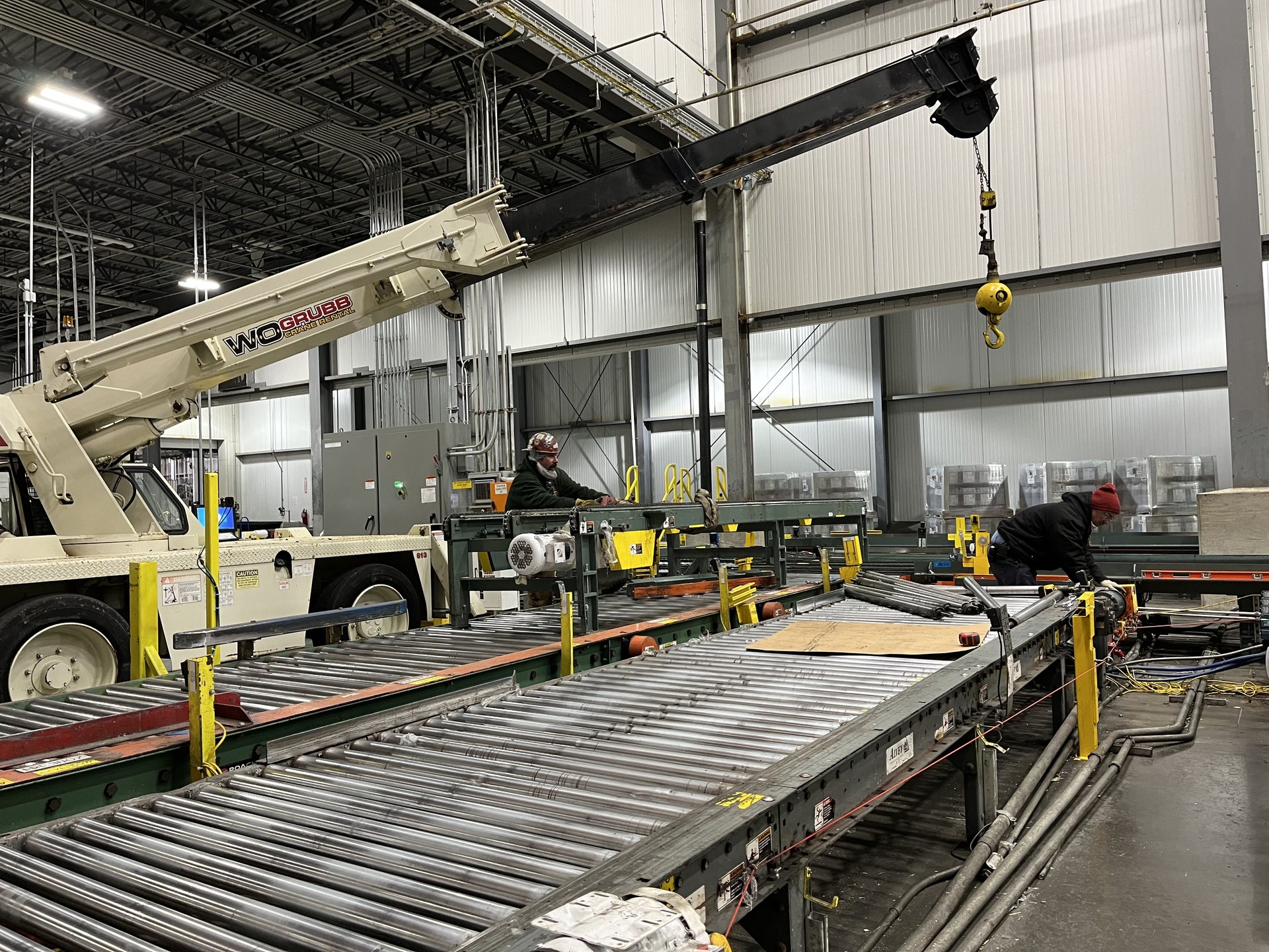 Riggers setting a conveyor line with a carry deck crane inside an industrial plant in Virginia