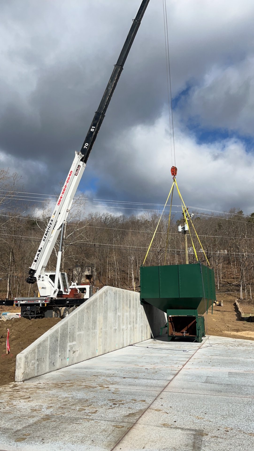 Boom truck crane rigging a trash compactor onto a new concrete pad in Middletown, VA