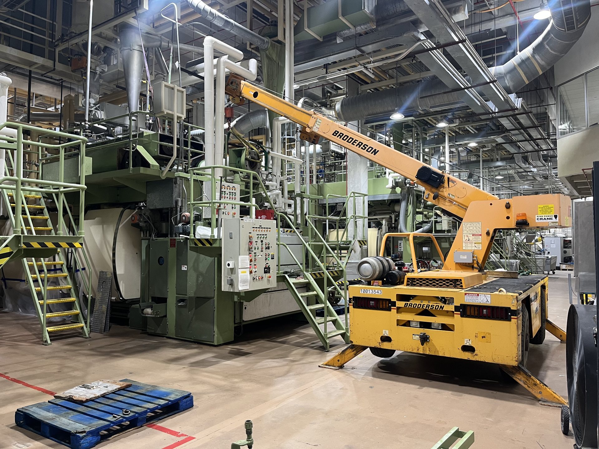 Pick and carry crane staged beside a production machine in a Virginia mill