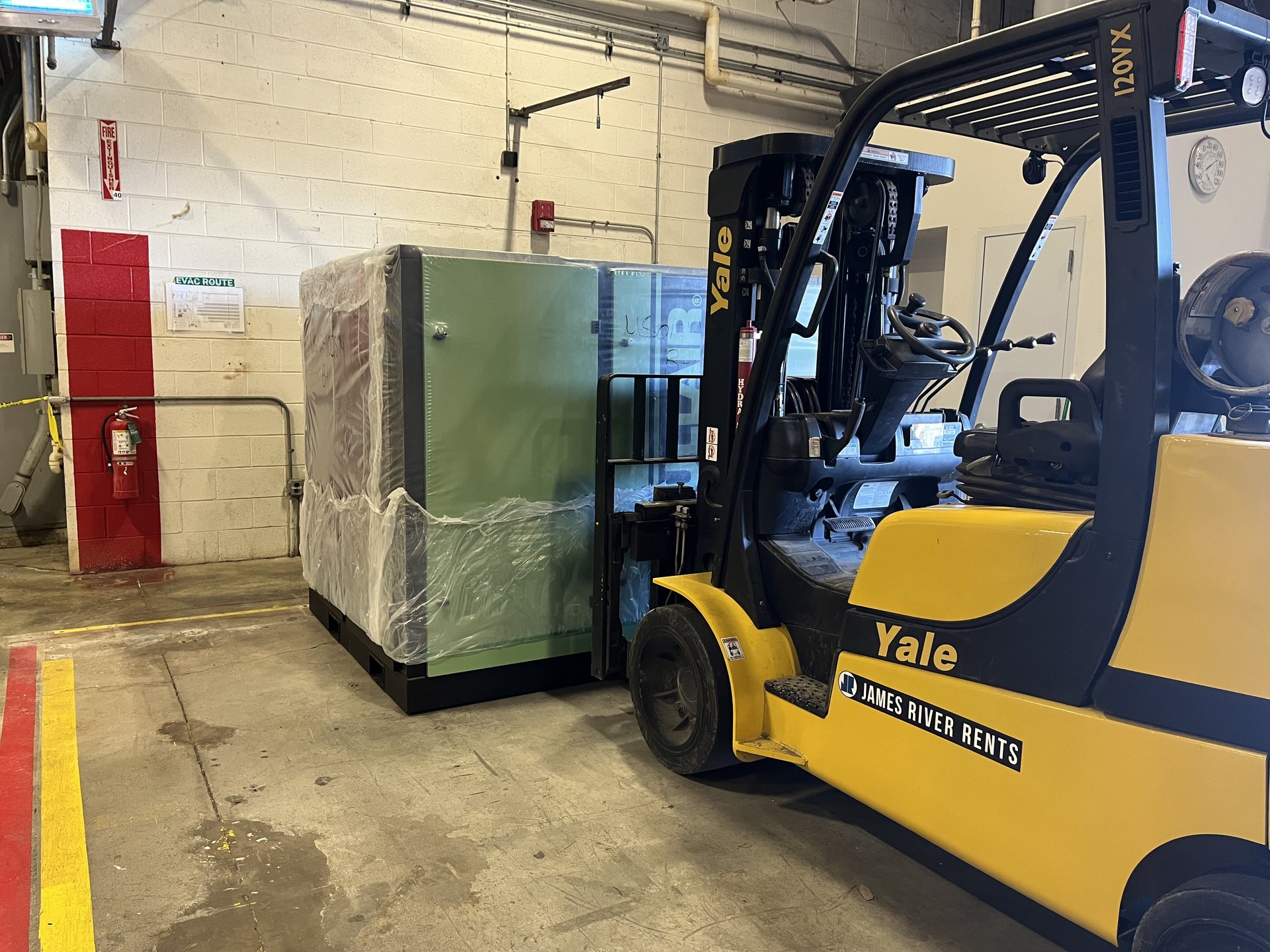 Forklift moving a wrapped electrical control cabinet inside a Virginia plant