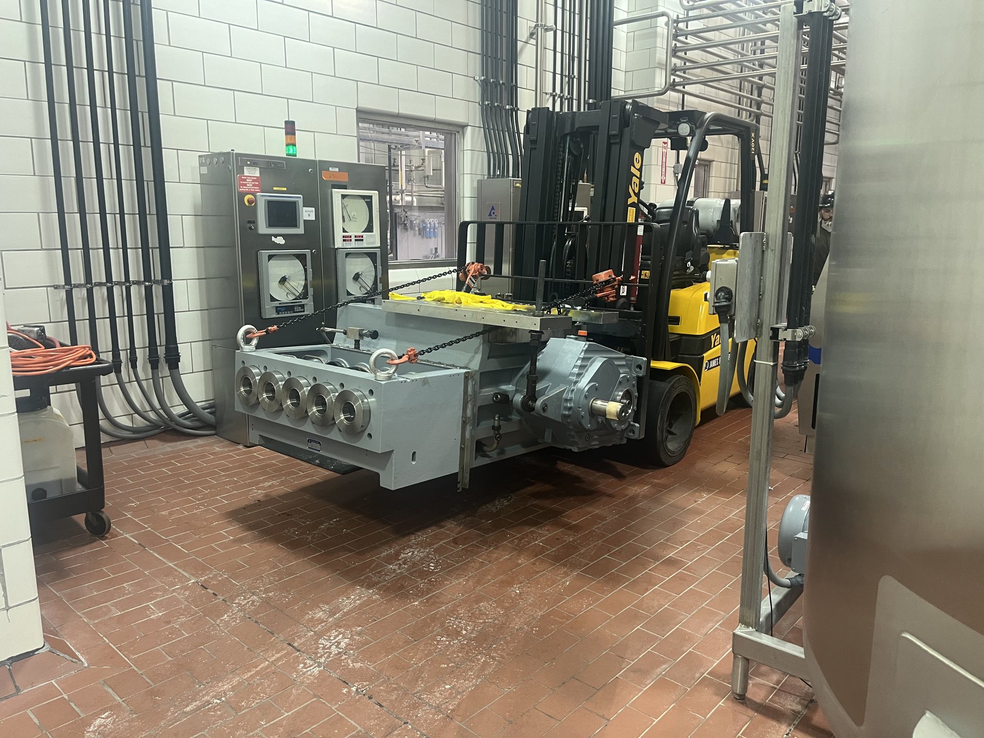 Forklift moving a homogenizer skid into a food plant process room in Virginia
